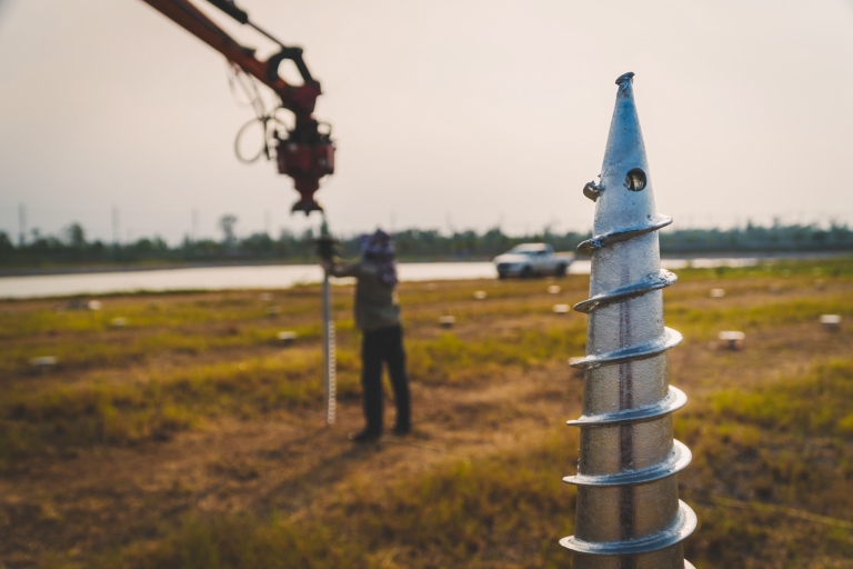 technician-installing-ground-screw-mounting-structure-solar-panel-solar-farm